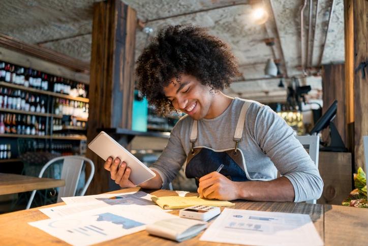 Black business owner writing notes on paper sitting at a table